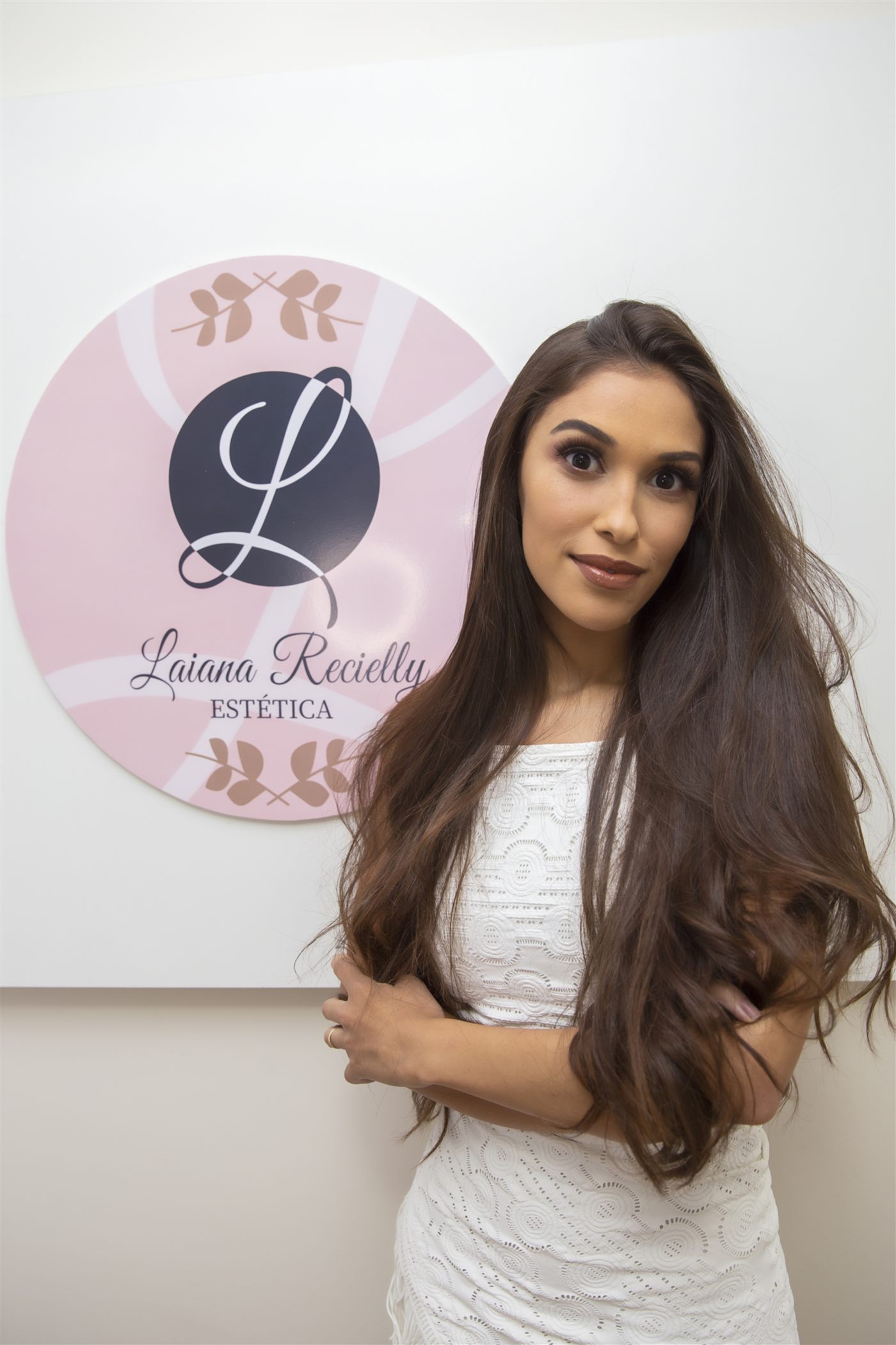 Laiana Recielly em frente à parede com o logo da clínica